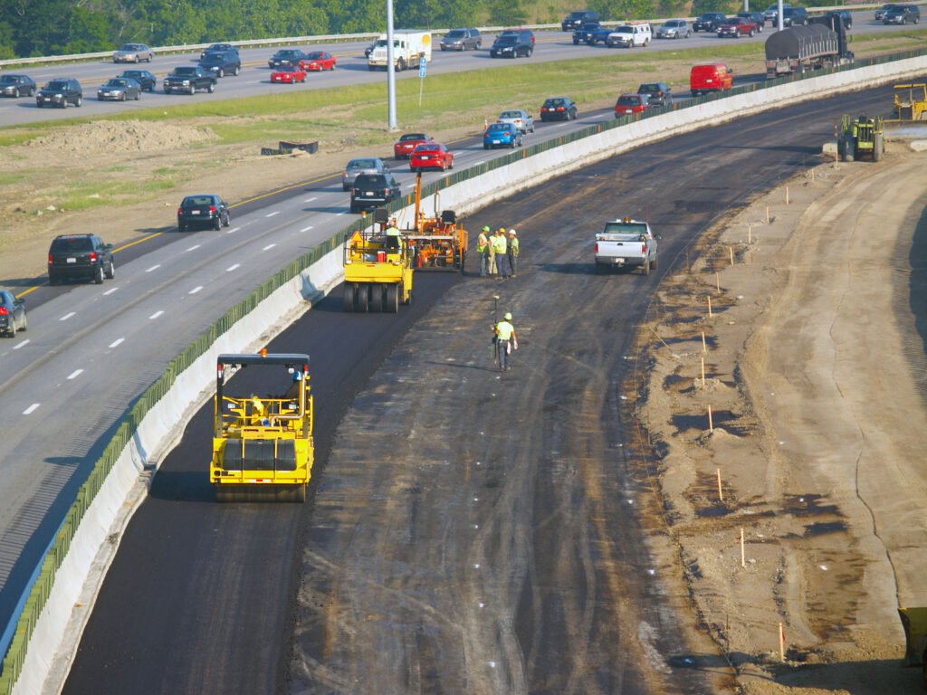 Workers laying asphalt in freeway construction zone